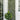 A tall green leafy lattice wall panel mounted on a white porch wall, styled with potted plants in woven baskets beside a glass door.